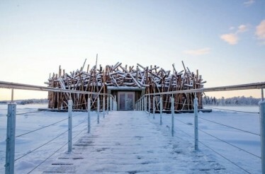 A wooden walkway leads to the Ecolyx Arctic Bath, surrounded by snow